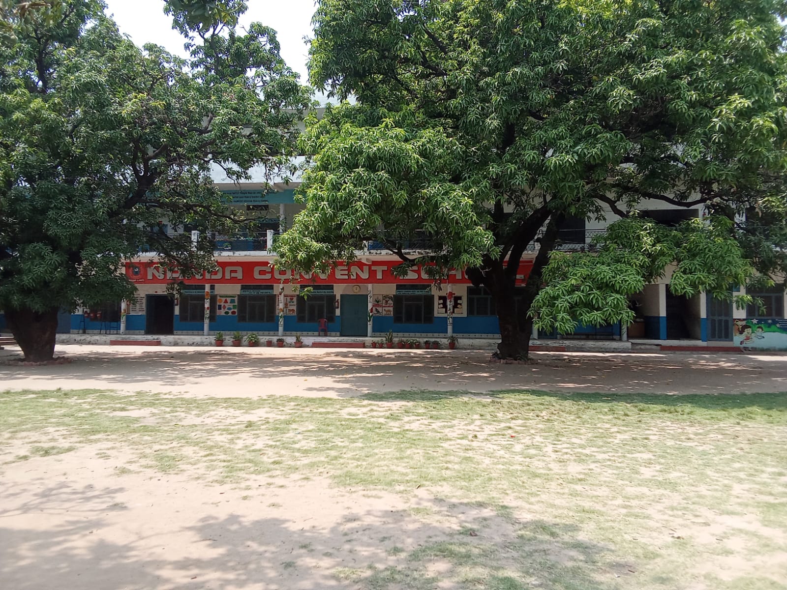 Nanda Convent School building, framed by mango trees in the school grounds